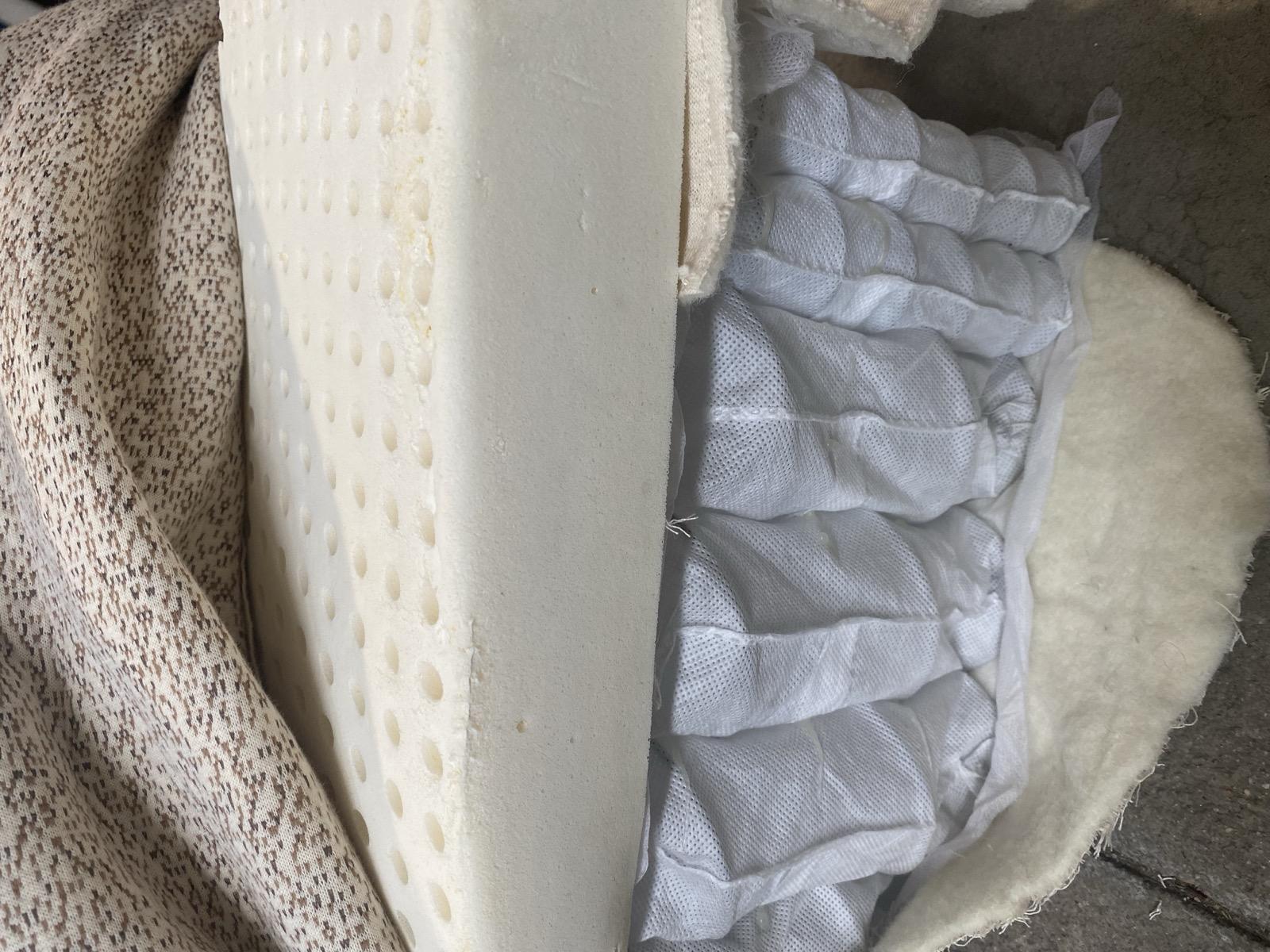 Natural latex mattress layer on top of innerspring coils showing open-cell structure for ventilation